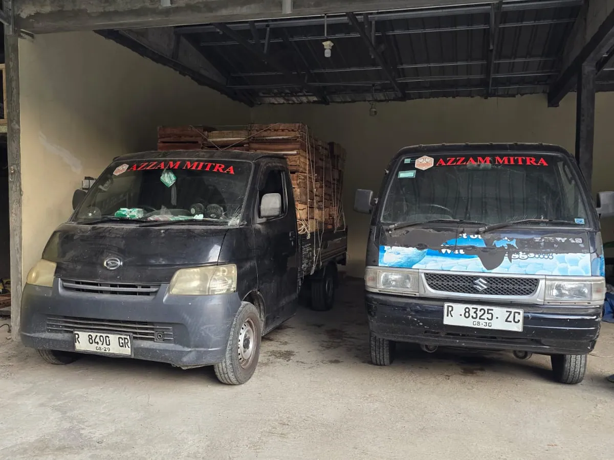 Dua armada pick-up Azzam Mitra bermerek terparkir di area bongkar muat gudang
